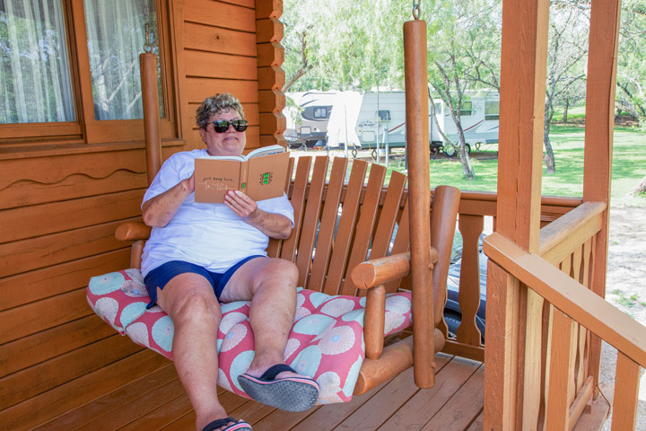 woman sitting on a cabin porch swing in Miller creek rv park