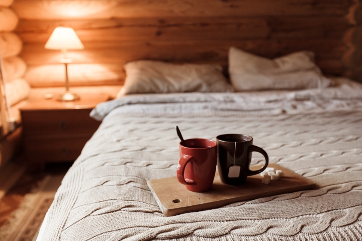 bed inside a cabin with two cups of tea