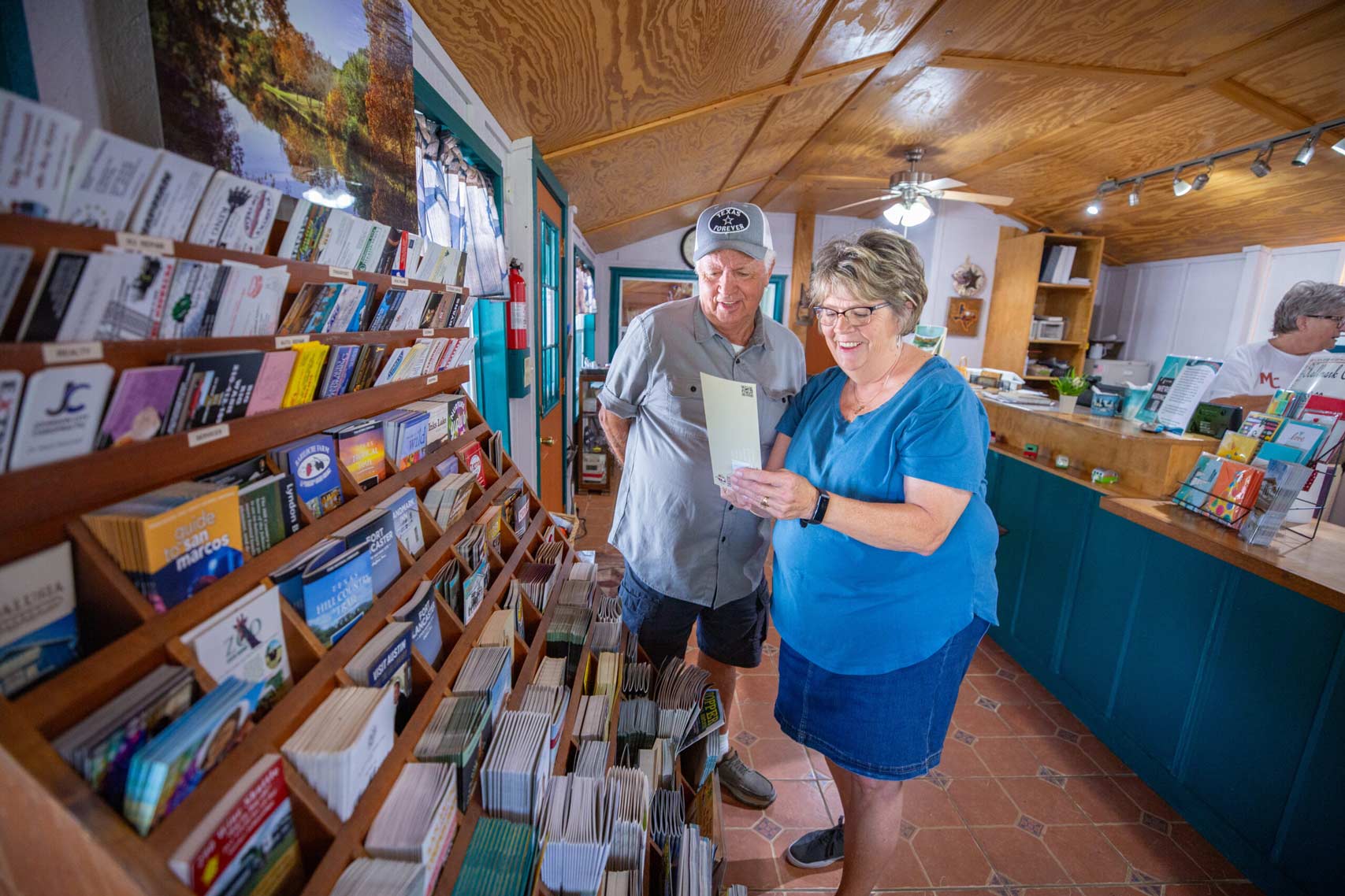 A senior couple browsing through a collection of travel guides and local maps at the reception area of a 55 and older RV park in Texas