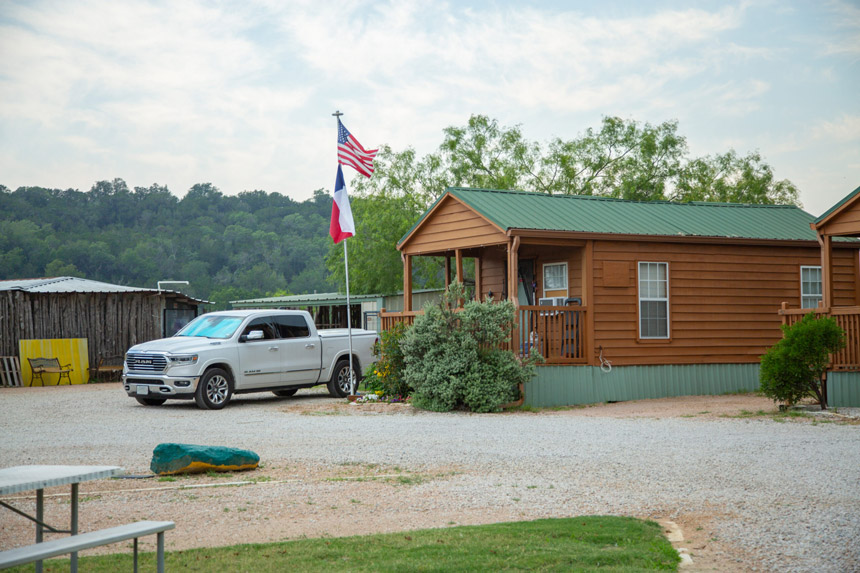 Cozy Johnson City Texas cabin rental with a welcoming porch and rustic charm, under Texas and United States flags