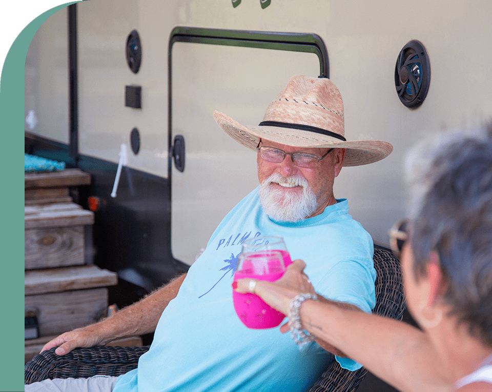 Man in straw hat enjoying a drink outside his RV at one of the RV parks near Dripping Springs, TX