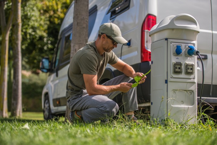 Man Attaching Electric Plug to RV Park Hookup