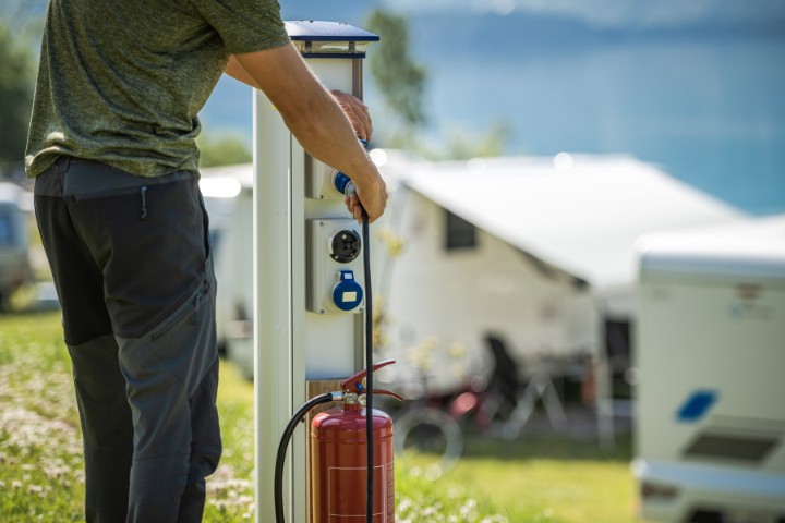 rver connecting an RV to a utility hookup at a campsite