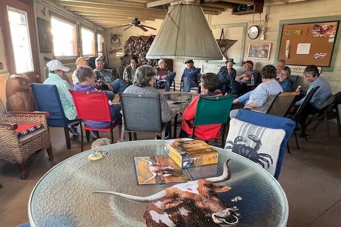 Large group of people seated in a circular arrangement around an indoor fire pit