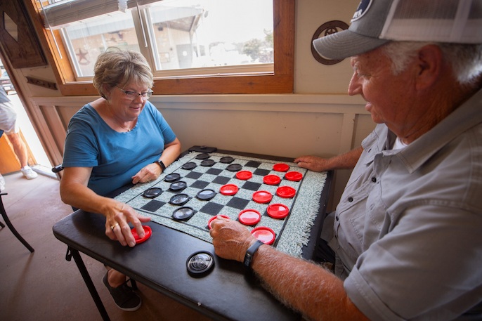 Senior couple playing a game of checkers at a table by a window