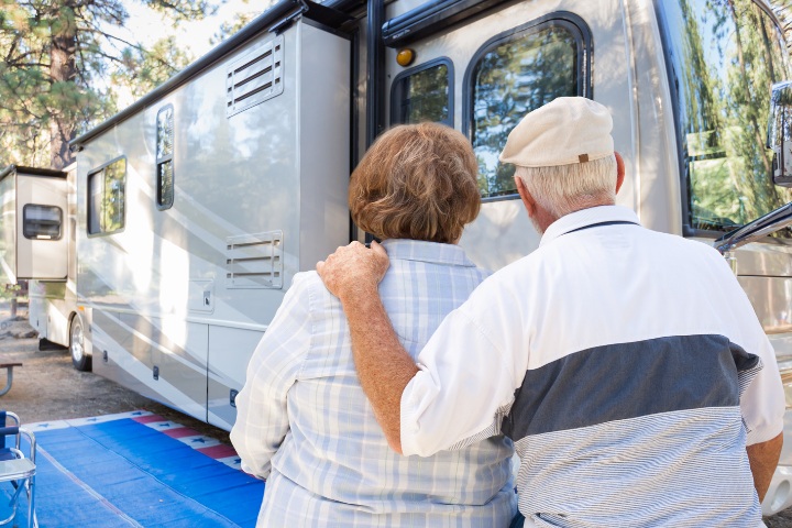 retired couple standing with their backs to the camera, looking at their RV