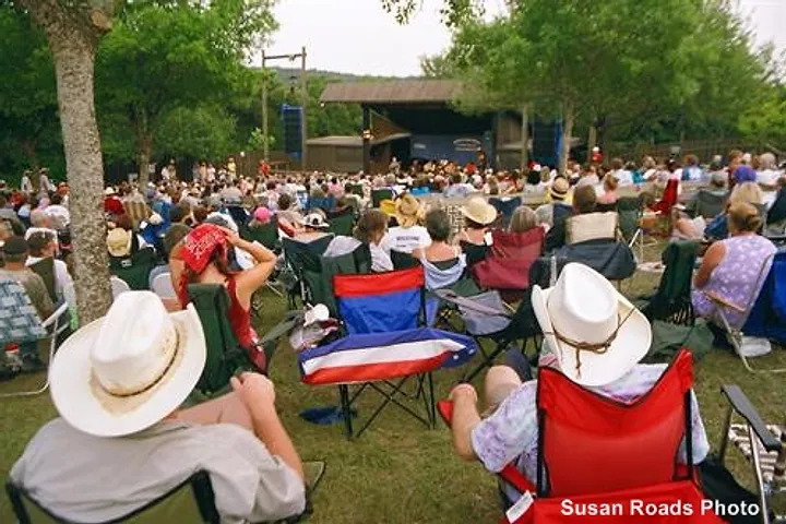 Crowd of festivalgoers seated outdoors, enjoying live music at the Kerrville Folk Festival