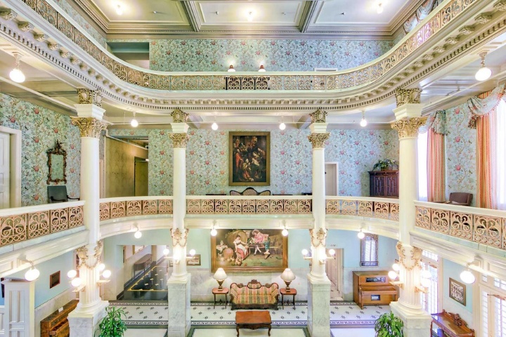 The elegant interior of the historic Menger Hotel in San Antonio, featuring ornate columns, floral wallpaper, and intricate balcony railings