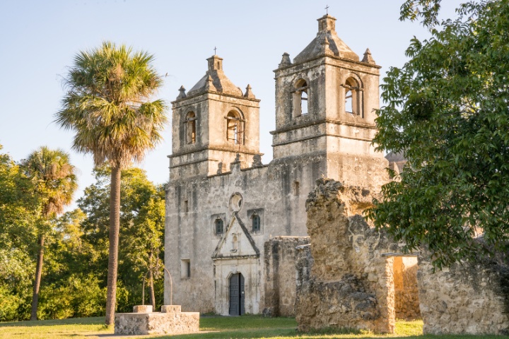 The well-preserved architecture of Mission Concepción in San Antonio, showcasing its iconic bell towers and rustic stone ruins under a clear sky