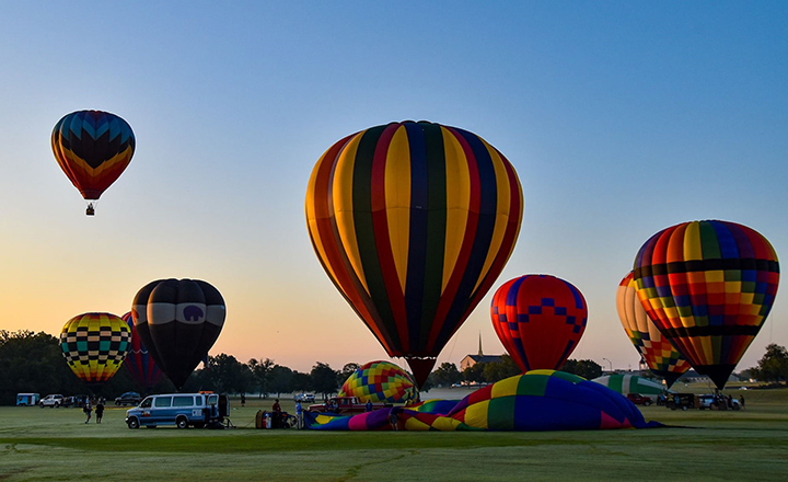 Colorful hot air balloons being inflated and taking flight at the Plano Balloon Festival