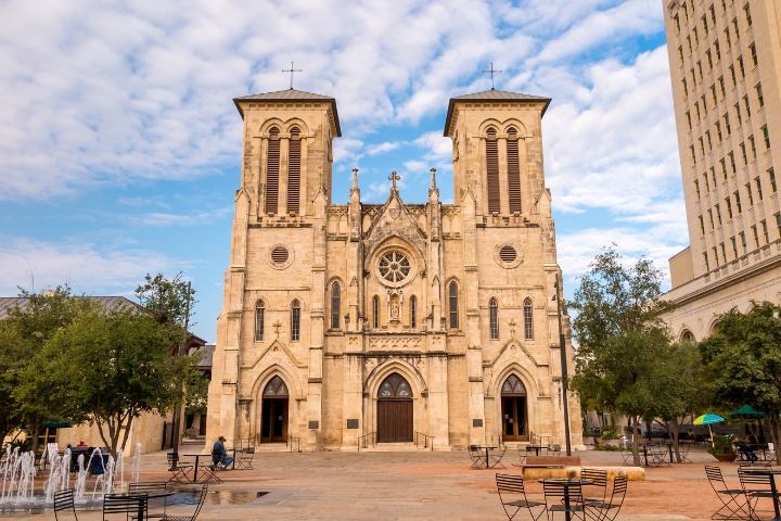 Front view of the San Fernando Cathedral in San Antonio, a significant landmark, with a clear sky and an empty courtyard