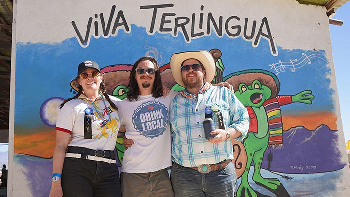 Attendees posing in front of a vibrant mural at the Terlingua Chili Cook-Off festival