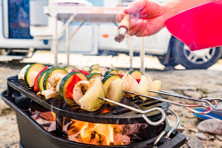 Vegetable skewers being grilled over an open flame during an RV camping trip