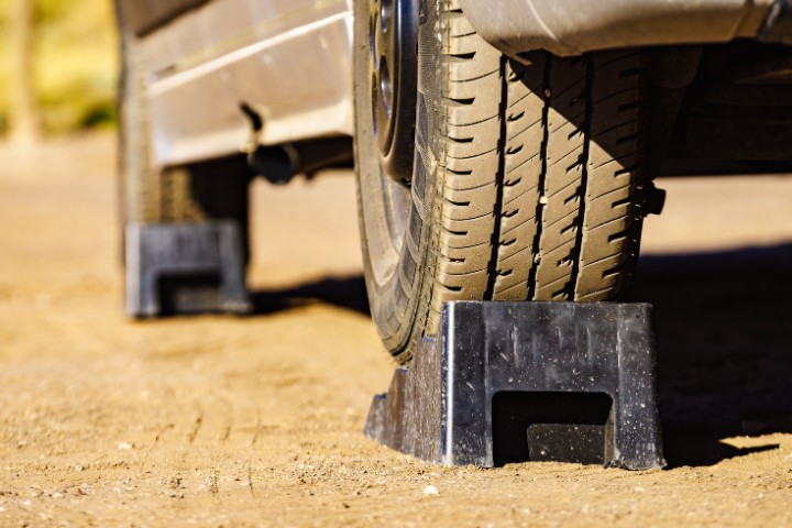 An RV tire resting on a leveling block on a dirt surface during a camping trip