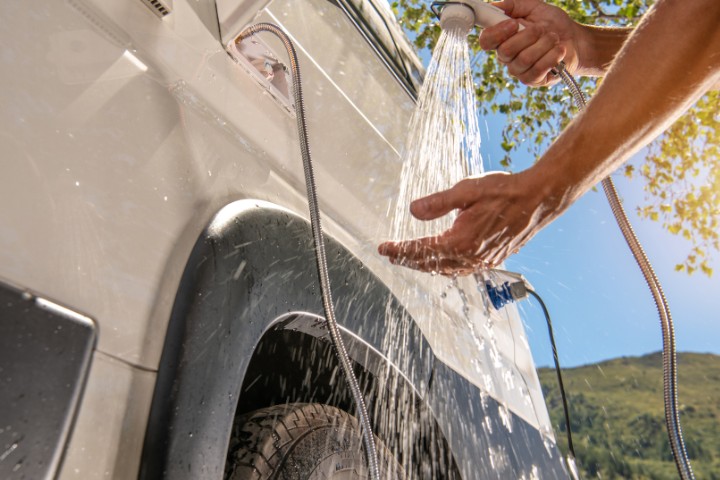 Rver rinsing hands with an external shower attached to an RV