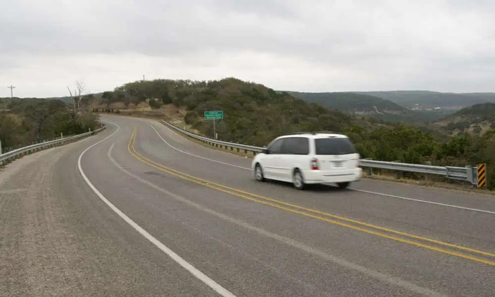 Vehicle driving along the winding Devil’s Backbone on Ranch Road 32, a scenic route in Texas Hill Country popular with motorcyclists