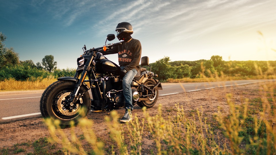 Biker wearing a helmet on a Harley-Davidson motorcycle parked on a rural road in Hill Country, Texas