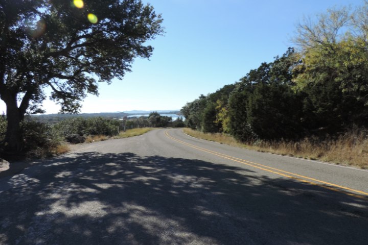 Quiet stretch of Park Road 4 with distant lake views, a popular route for RVing motorcyclists in Texas Hill Country