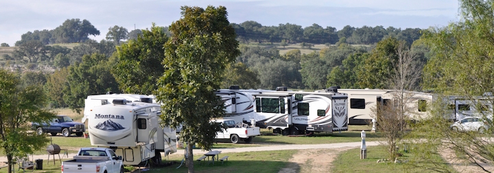 Scenic RV sites at Guadalupe River RV Park with greenery and hill country views in the background