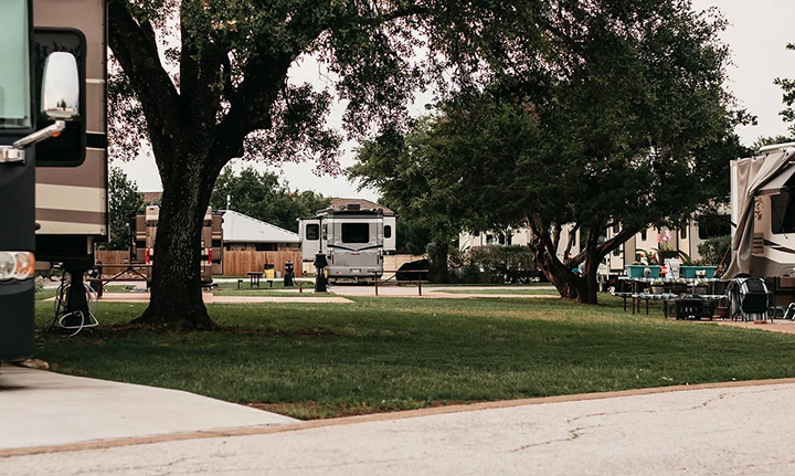 Well-maintained RV campsite at Sunset RV Resort with grassy areas and shaded trees