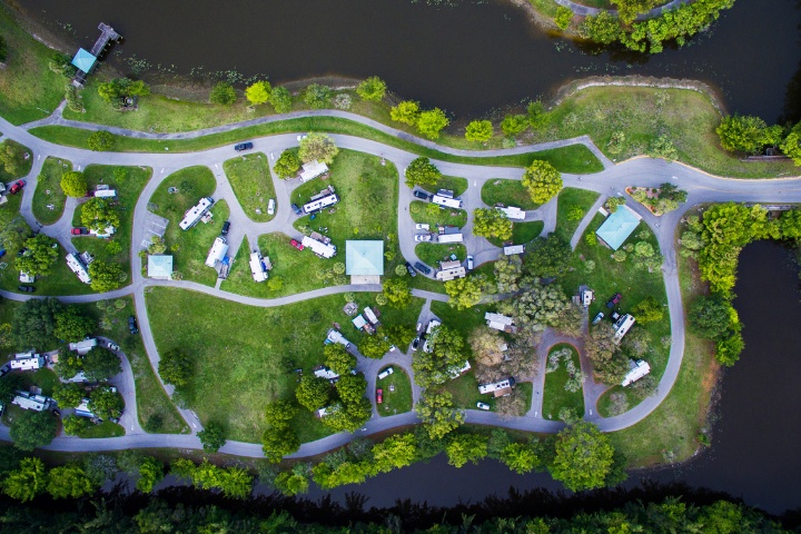 Aerial view of an RV campground with winding roads, campsites, and a nearby lake