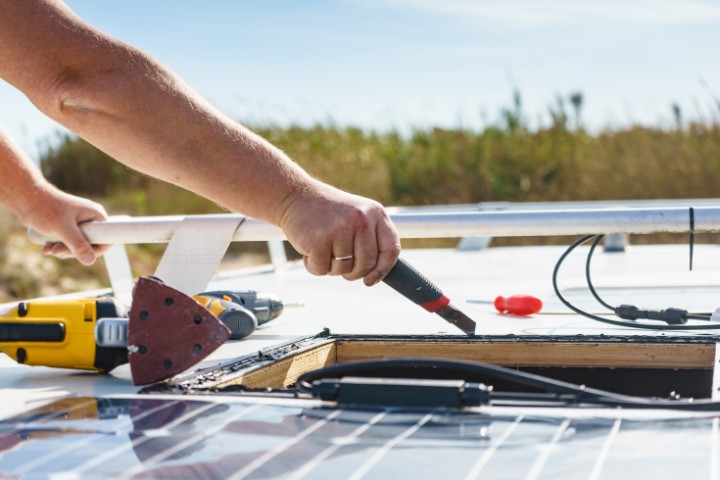 A man working on the roof of a camper van, showcasing the importance of RV maintenance