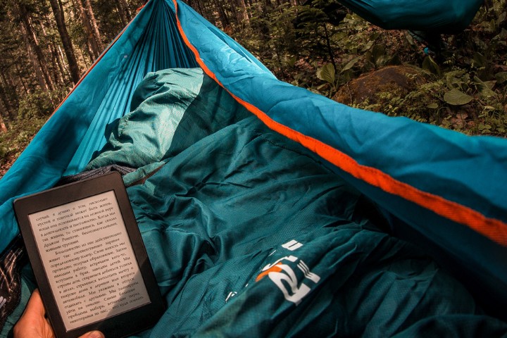 A person reading on a Kindle while camping, showcasing a peaceful aspect of RV living and availability of digital alternatives