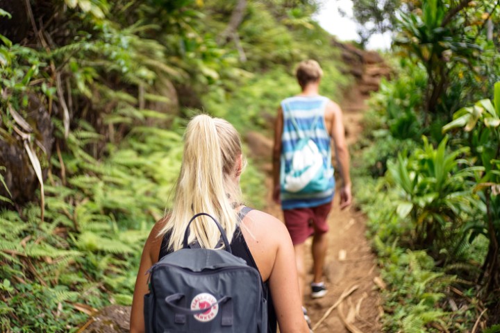 A woman and man walking along a forest trail, showcasing outdoor activities for RV travelers