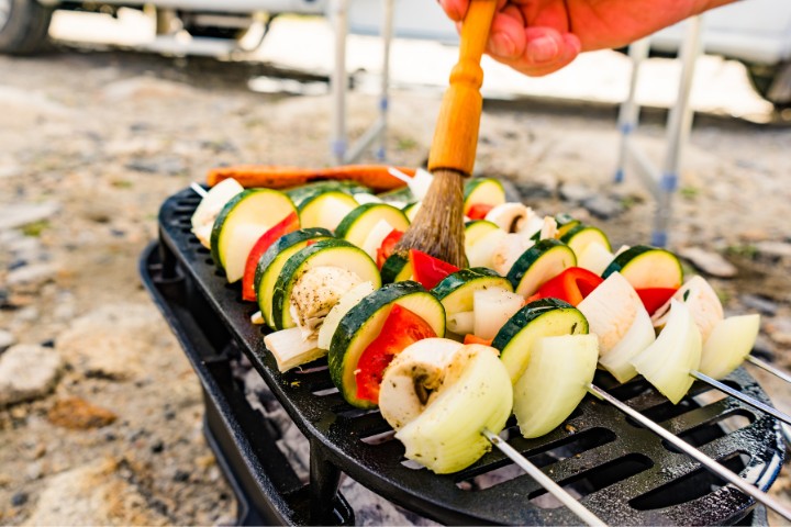 Grilling fresh vegetables on a portable BBQ grill for an outdoor RV camping meal