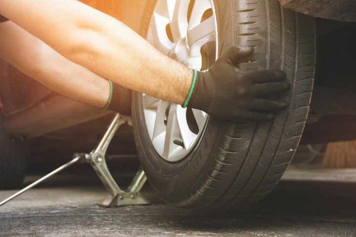 Changing a tire on an RV with a jack and safety gloves for roadside emergencies.