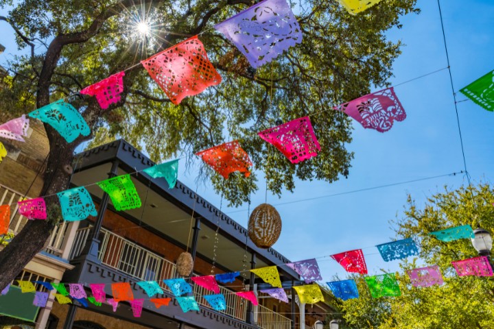 Vibrant papel picado flags draped above a festive street in San Antonio’s historic arts district