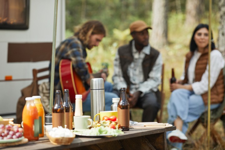 Relaxing RV camping setup with friends enjoying outdoor dining and music