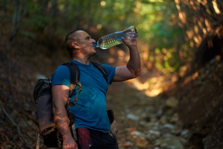 Hiker drinking water on a shaded hiking trail in Texas Hill Country