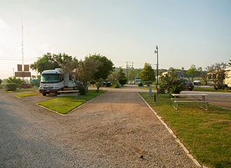 austin-s3-rv-sites Spacious RV site at a park around San Antonio, Texas, with a large RV and outdoor seating area bathed in the warm glow of a setting sun