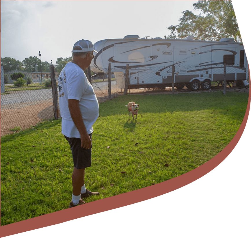 Guest with a dog in a grassy RV park area near San Antonio, Texas