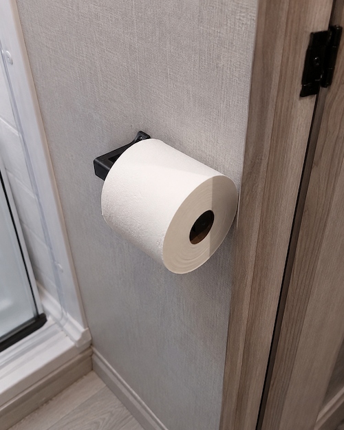 Roll of RV safe toilet paper mounted inside a compact travel trailer bathroom