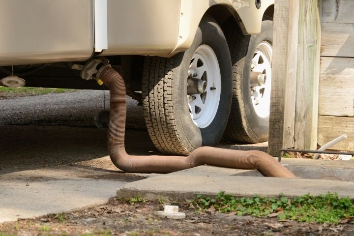 Waste hose connected beneath an RV illustrating proper sewage disposal for long-term RV occupancy