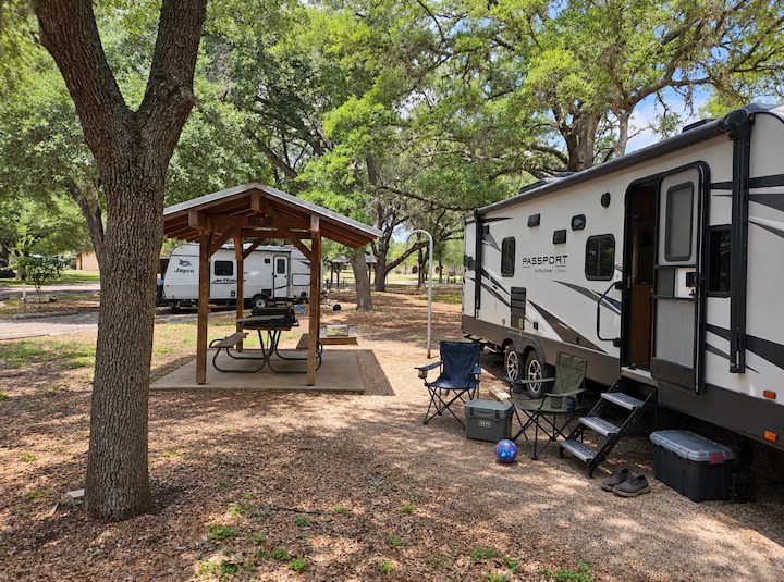 Shaded RV camping site beneath mature oak trees at Blanco State Park