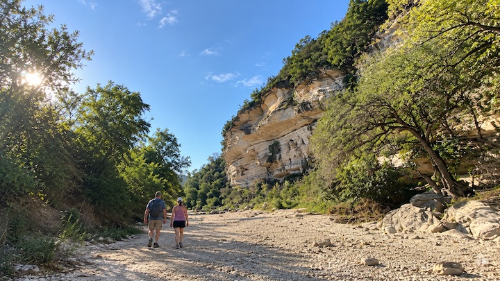 Hikers walking through a dry limestone creek bed at Barton Creek Greenbelt